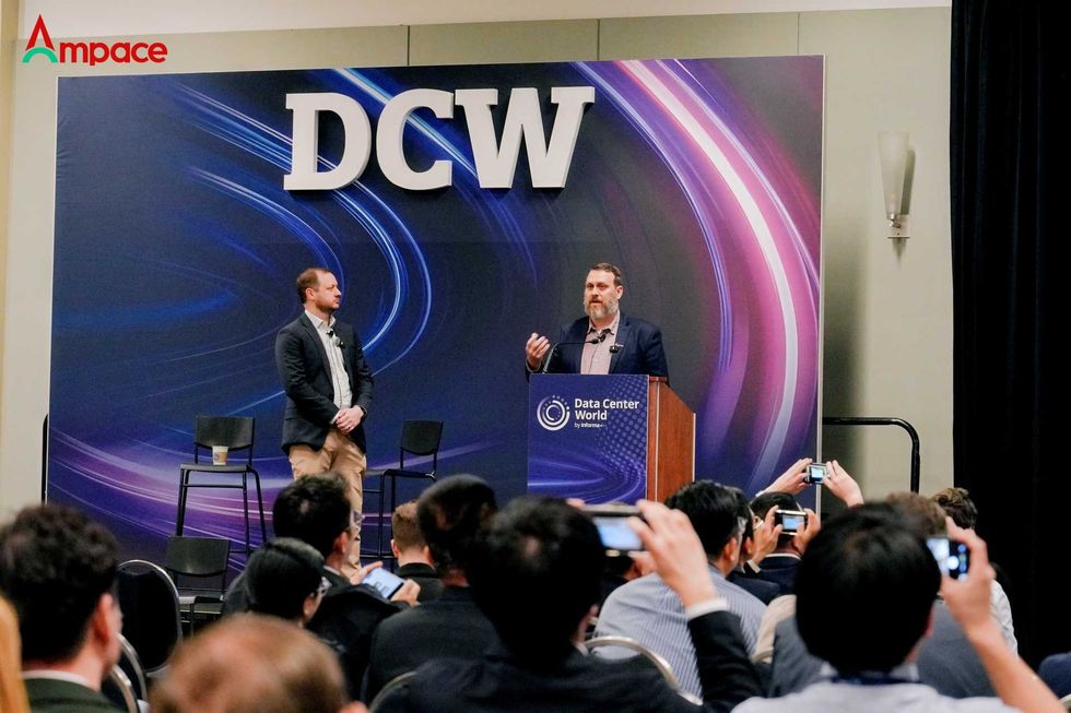 Speaker at DCW conference presenting on stage to an audience with phones raised